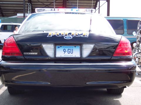 2001 Ford Crown Victoria - Rear view of a black 2001 Ford Crown Victoria police car, identified by its 'POLICE' badging and distinctive taillights.