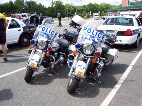 2001 Ford Crown Victoria - Two police motorcycles are parked side-by-side in a lot, with a police car visible behind them.