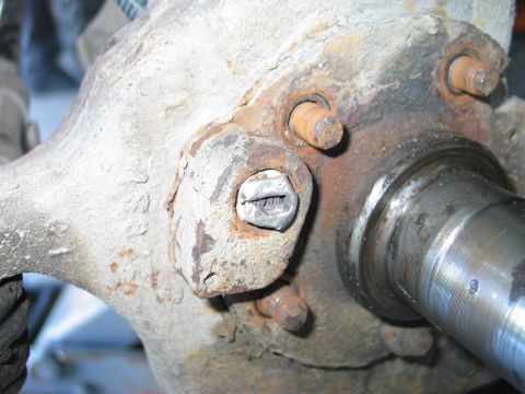 1995 Ford Bronco - Extreme close-up of a rusty steering knuckle and spindle on a solid front axle, with the polished bearing surfaces of the spindle shaft pro…