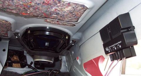 1985 Ford LTD Crown Victoria - Underside of a rear deck seen from inside a car trunk, showing a 6x9 speaker mounted on a black bracket with a black component crossover ne…