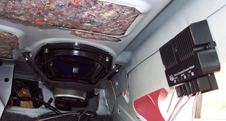 6x9 speaker and component crossover box mounted under a car's rear deck, seen from the trunk