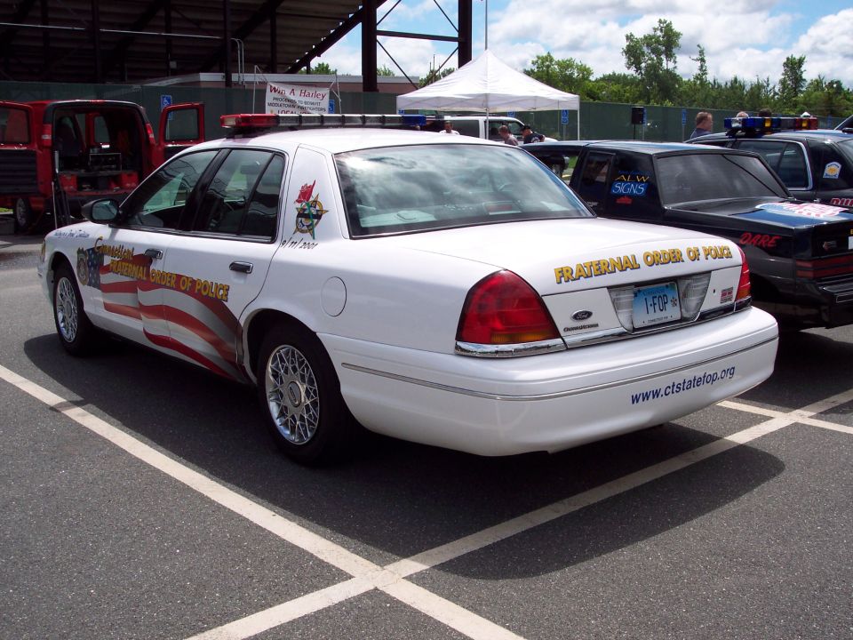 White 2001 Ford Crown Victoria police car with "Fraternal Order of Police" text and American flag graphic on the side