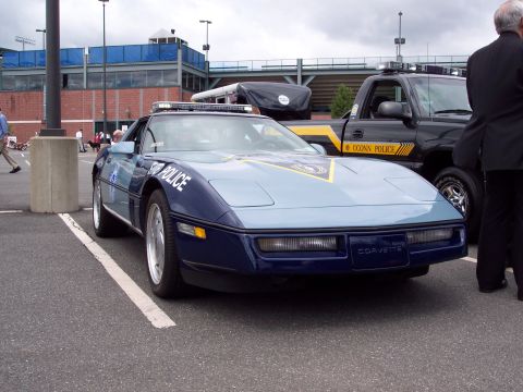 2001 Ford Crown Victoria - A police Corvette and a UCONN POLICE pickup truck are parked side-by-side at an outdoor event.