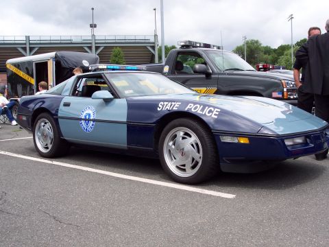 2001 Ford Crown Victoria - A two-tone blue and light blue Chevrolet Corvette is marked as 'STATE POLICE' and has a light bar on its roof.