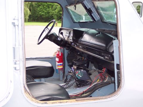 2001 Ford Crown Victoria - The interior of a vehicle is visible, a steering wheel, dashboard, and a red fire extinguisher mounted to the side.