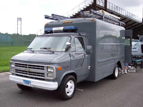 2001 Ford Crown Victoria - A custom utility van with a large cargo box and equipment rack is parked outdoors.