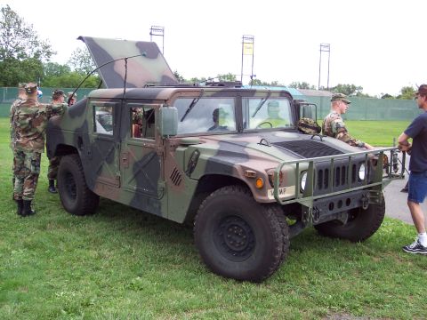 2001 Ford Crown Victoria - A military Humvee is parked on a grassy field with several people in uniform around it.