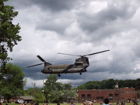 2001 Ford Crown Victoria - A military Chinook helicopter is seen in flight above a crowd gathered outdoors.