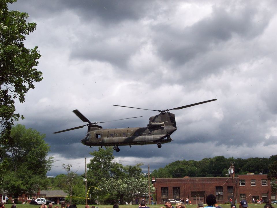 Chinook helicopter flying low over a residential area with trees and buildings