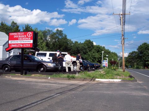 2001 Ford Crown Victoria - Police vehicles and a white SUV are parked in front of a Connecticut Insurance Exchange office on a sunny day.