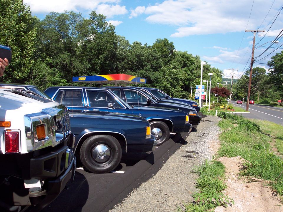 Blue 2001 Ford Crown Victoria parked in a row, side view. A white Hummer is in the foreground