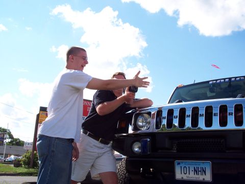2001 Ford Crown Victoria - Two men stand near a Hummer H2, one taking a photo, under a partly cloudy sky.