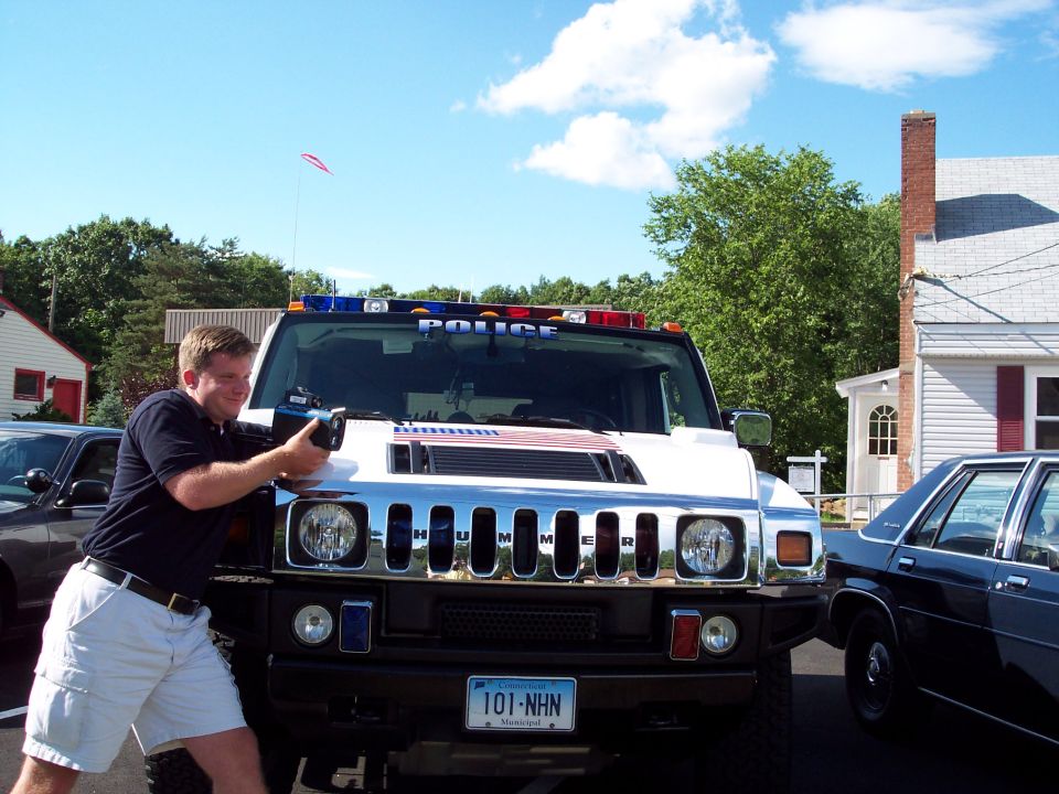 Front view of a white Hummer H2 police SUV with "POLICE" on the light bar