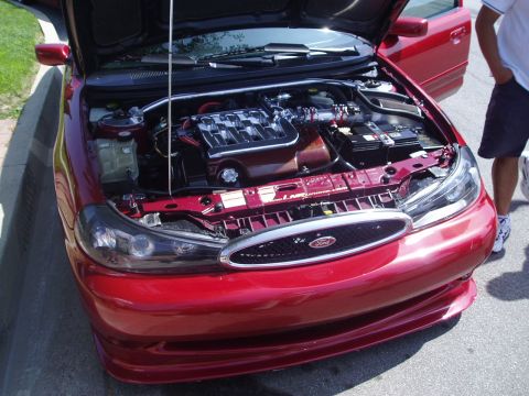 1993 Ford Taurus - Front view of a red Ford sedan's engine bay, a modified engine and custom grille.