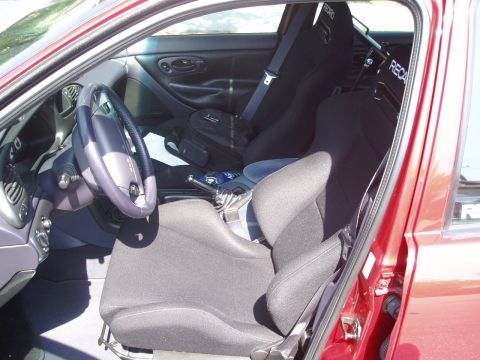 1993 Ford Taurus - The interior of a red car shows racing seats and a manual transmission shifter.