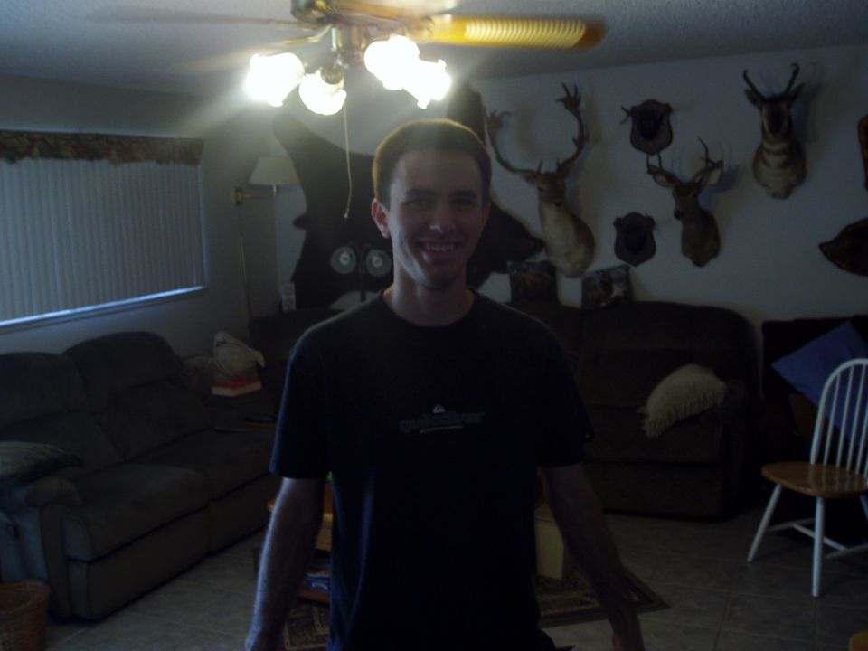Man stands in a living room with mounted deer heads on the wall and two couches