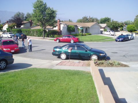 1993 Ford Taurus - Several sedans are parked on a suburban street on a sunny day.