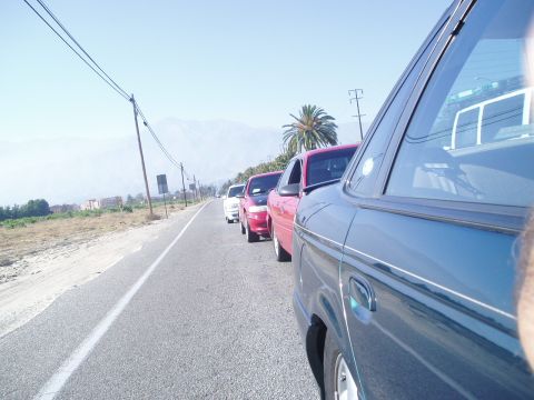 1993 Ford Taurus - A line of vehicles travels down a highway under a clear blue sky.