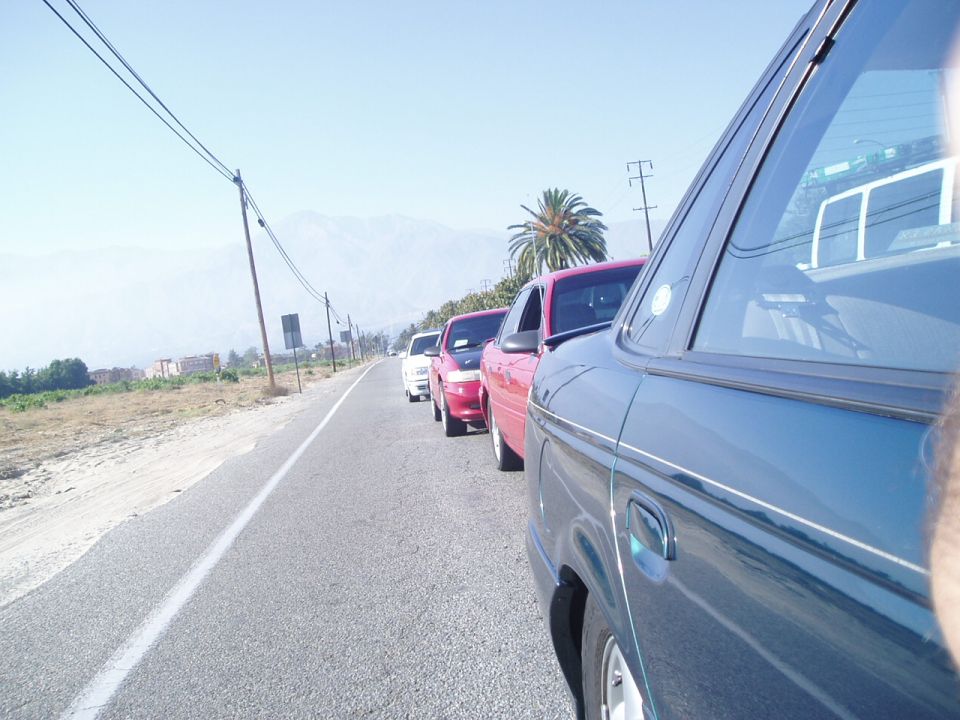 Cars lined up on a road with mountains in the background