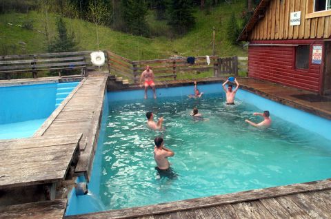 1996 Ford Bronco - A group of people enjoy a swim in a pool surrounded by trees and a rustic wooden structure.