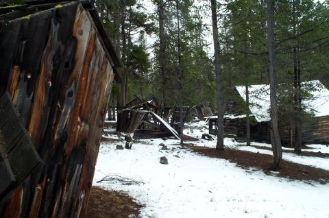 1996 Ford Bronco - Abandoned wooden structures in a snowy forest setting, with some buildings collapsed.