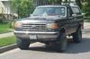 1988 Ford Bronco - A black Ford Bronco from the late 1980s is parked on a residential street.