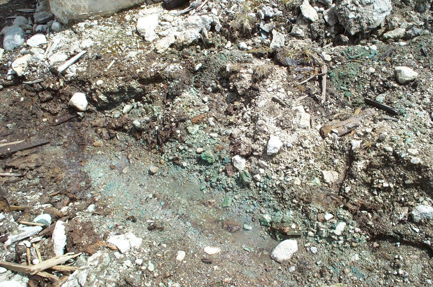 Dirt and rocks with green mineral deposits