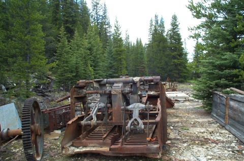 1996 Ford Bronco - Abandoned industrial equipment sits rusting in a wooded area.