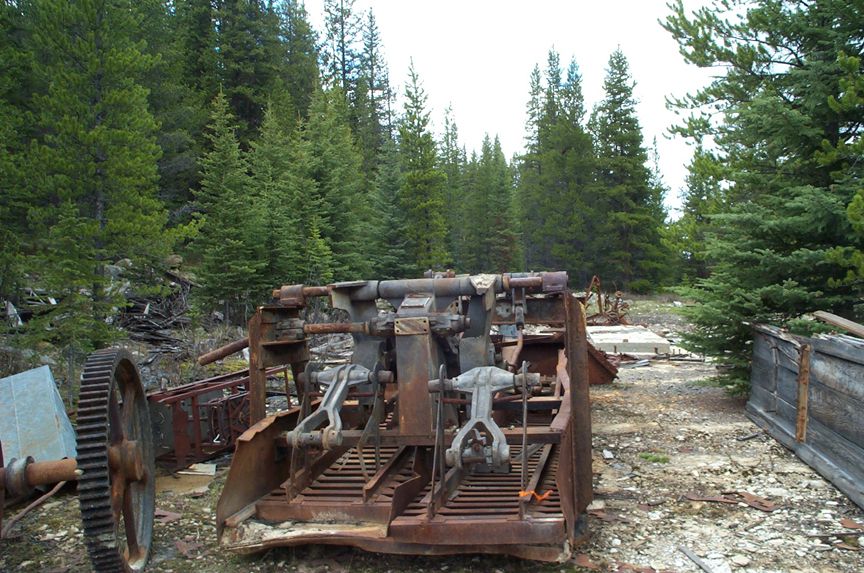 rusted industrial machinery with large gear in forest setting
