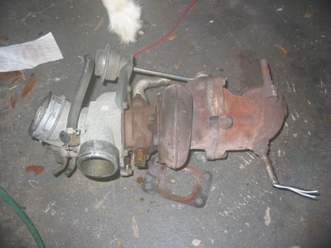 1985 Ford LTD Crown Victoria - Turbocharger assembly shown on a concrete floor, likely removed from a vehicle.