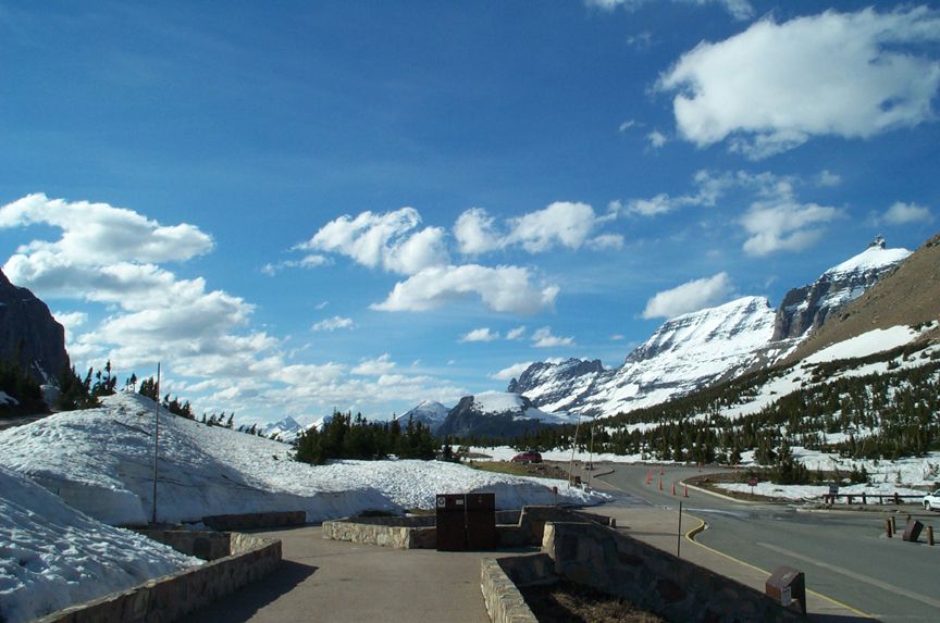 mountain road with snow patches and blue sky with clouds