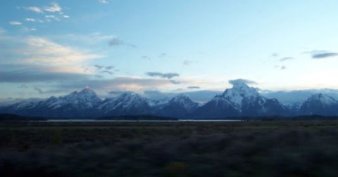 1996 Ford Bronco - A scenic view of snow-capped mountains and a lake under a vast, cloudy sky, with a website logo in the corner.