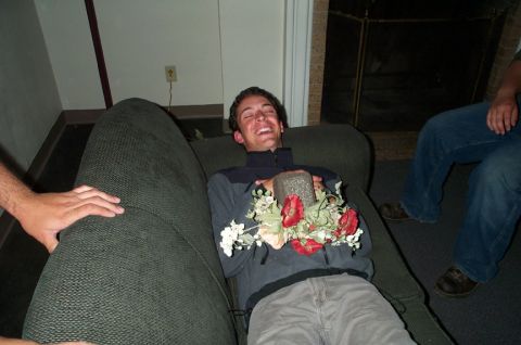 1996 Ford Bronco - A man laughs while holding a rock and a bouquet of flowers on a couch, with another person visible to the right.