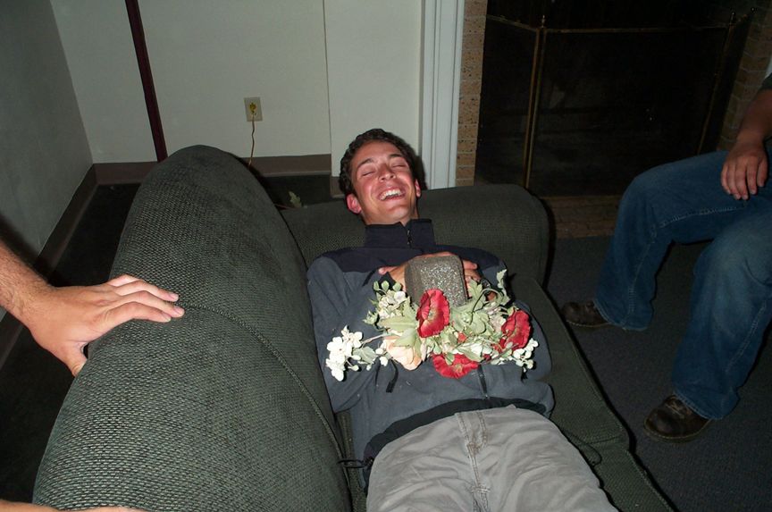 Man laughing on couch holding a rock and flowers