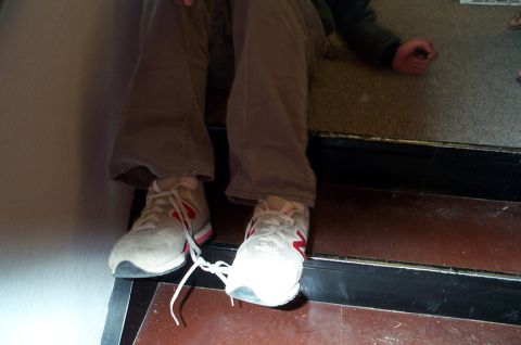 1996 Ford Bronco - A person is seated on a set of stairs, their feet clad in white sneakers with distinctive red markings.