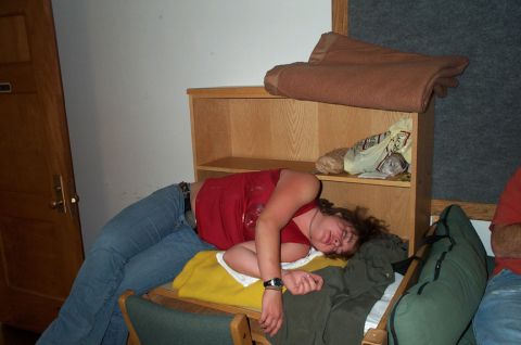 1996 Ford Bronco - A person is sleeping on a chair, surrounded by blankets and a shelf with items.
