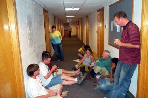 1996 Ford Bronco - A group of people are gathered in a hallway, sitting on the floor and holding drinks.