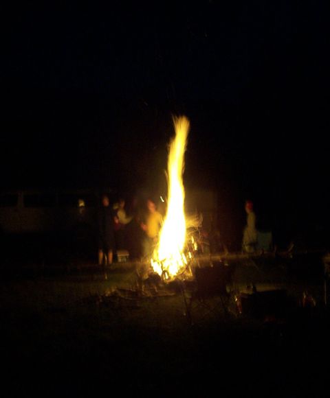 1996 Ford Bronco - A group of people stand around a large bonfire in the dark.