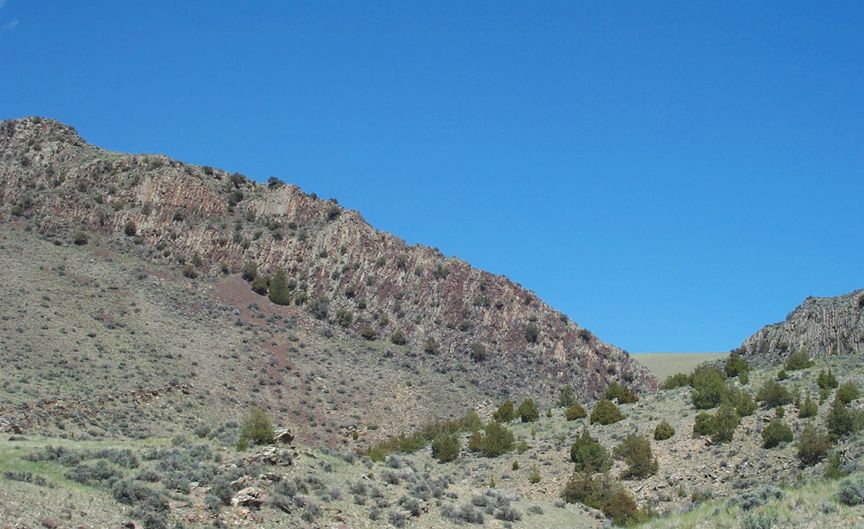 Mountainous landscape with sparse vegetation under a clear blue sky