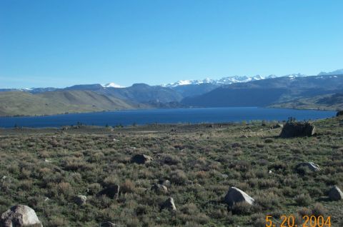 1996 Ford Bronco - A vast blue lake is surrounded by rolling hills and snow-capped mountains under a clear sky.