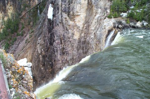 1996 Ford Bronco - A powerful waterfall plunges over a cliff face into a turbulent river below, surrounded by rocky terrain and sparse vegetation.