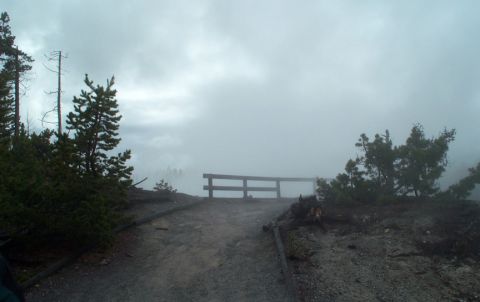1996 Ford Bronco - A misty scene with a wooden railing and pine trees, suggesting a natural park or viewpoint.