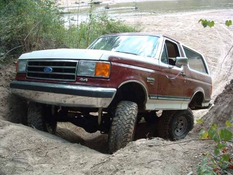 1993 Ford Bronco - This Ford Bronco is navigating a challenging off-road terrain with steep dirt inclines.