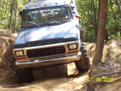 1987 Ford Bronco - A lifted Ford truck navigates a challenging off-road trail with steep inclines and tight turns.