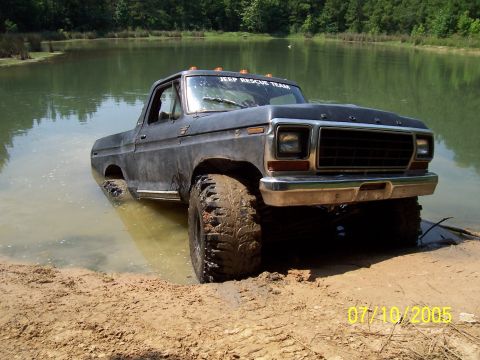 1987 Ford Bronco - This Ford Bronco is partially submerged in water, with its tires deep in mud.