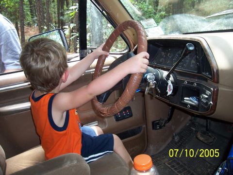 1987 Ford Bronco - Youngster pretends to drive a 1987 Ford Bronco, holding the steering wheel.