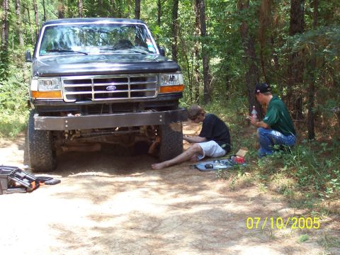 1987 Ford Bronco - Two men work on a dark gray Ford truck with an aftermarket bumper in a wooded area on July 10, 2005.