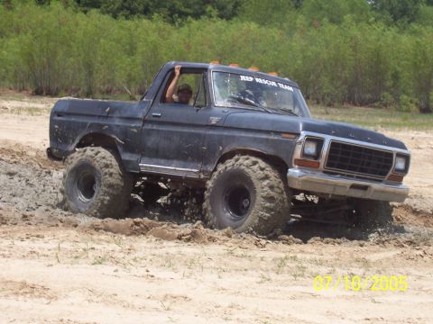 1987 Ford Bronco - This modified Ford Bronco, likely from the late 1970s, navigates a muddy off-road course.