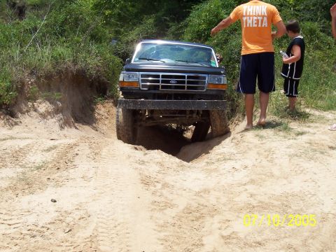 1987 Ford Bronco - A black Ford Bronco navigates a challenging off-road path on a sunny day.