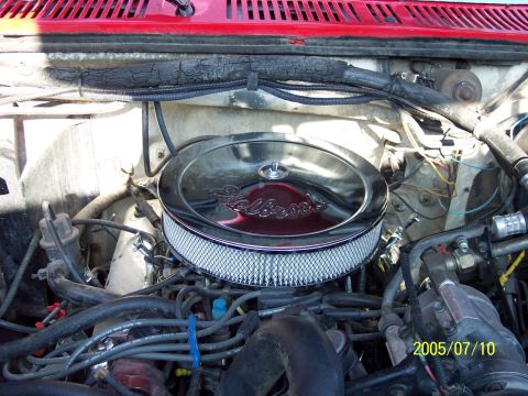 1985 Ford Bronco - Close-up of an engine bay showing an aftermarket air cleaner and various engine components.